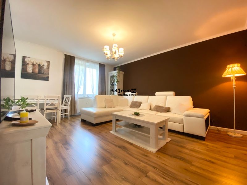 Wohnzimmer in einer 2-Zimmer-Wohnung mit Holzboden und bequemer Couch.