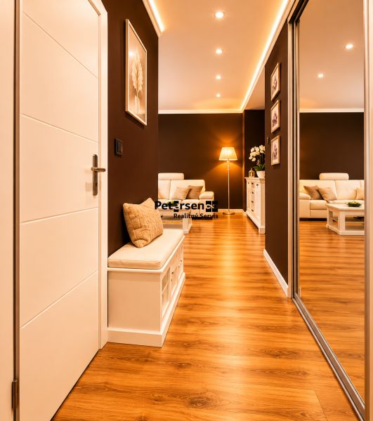 Der Flur in einer 2-Zimmer-Wohnung mit einem Boden in Holzoptik und einer bequemen Sitzgelegenheit.
