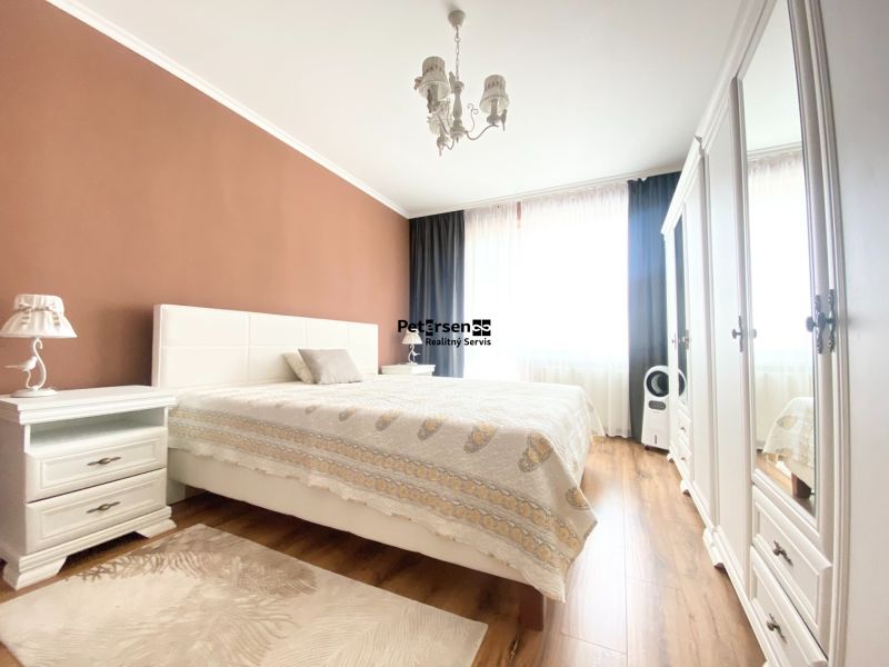 Hauptschlafzimmer in einer Zweizimmerwohnung mit Bett und Boden in Holzoptik.