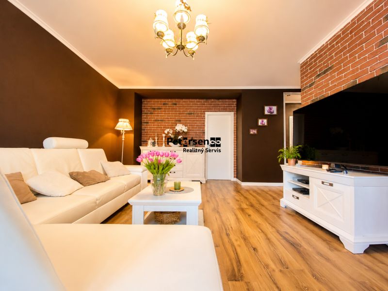 Wohnzimmer in einer 2-Zimmer-Wohnung mit Holzboden und weißen Möbeln.