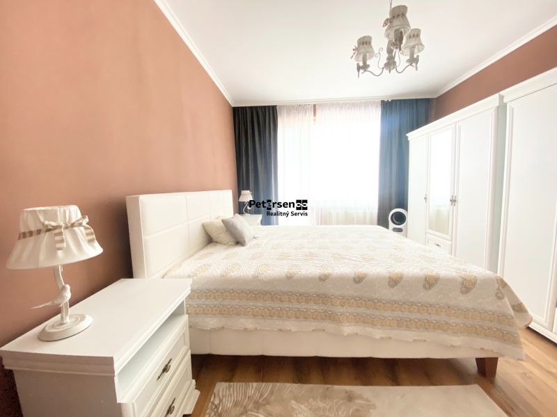Schlafzimmer in einer 2-Zimmer-Wohnung mit einem Doppelbett, weißen Möbeln und einem Boden mit Holzdekor.