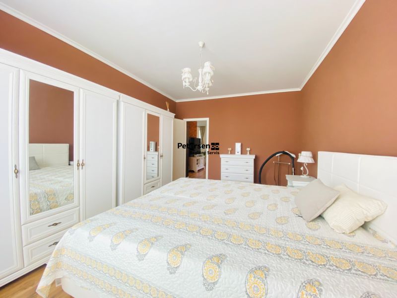 Schlafzimmer in einer 2-Zimmer-Wohnung mit weißen Möbeln und einem Bett auf dem Boden mit Holzdekor.