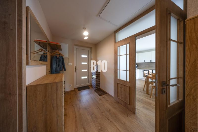 Eingangsbereich mit Schrank und Spiegel in einem Einfamilienhaus, Boden mit Holzdekor.