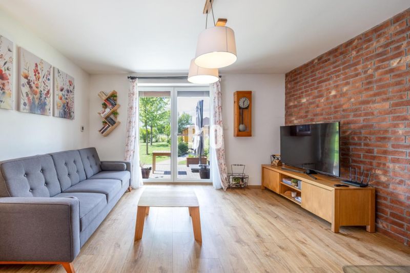 Wohnzimmer in einem Einfamilienhaus mit Ziegelwand, bequemer Couch und Holzboden.