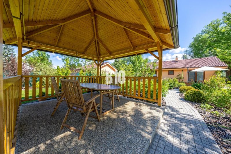 Ein hölzerner Pavillon mit Sitzgelegenheiten im Garten eines Einfamilienhauses in Bíkové Humence.