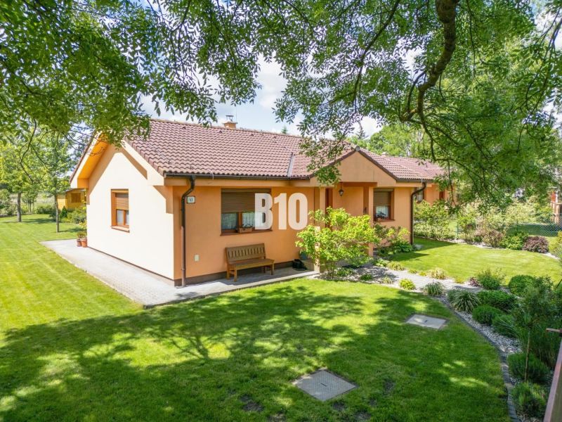 Ein Einfamilienhaus in Bíľkové Humence, umgeben von einem gepflegten Garten und grünem Rasen.