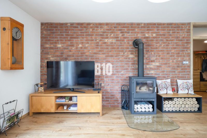 Ein Fernseher und ein Kamin an einer Ziegelwand, Holzboden, Einfamilienhaus.