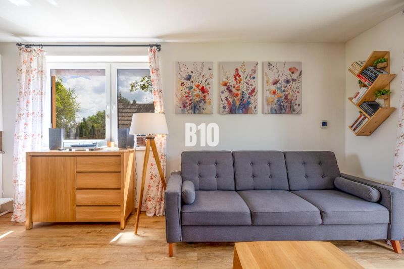 Wohnzimmer mit Sofa, Bildern und Holzboden in einem Einfamilienhaus.