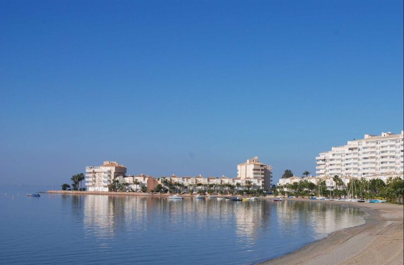 Die Küste mit Ferienwohnungen in La Manga del Mar Menor am ruhigen Meer und blauem Himmel.