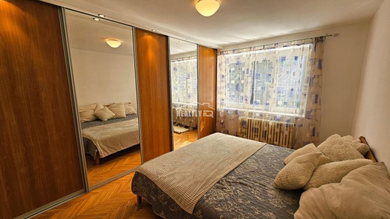 Schlafzimmer mit Schränken mit Schiebetüren und großem Spiegel in einer Zweizimmerwohnung.