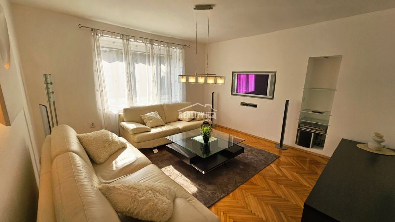 Wohnzimmer mit weißem Sofa und Holzboden in einer 2-Zimmer-Wohnung.