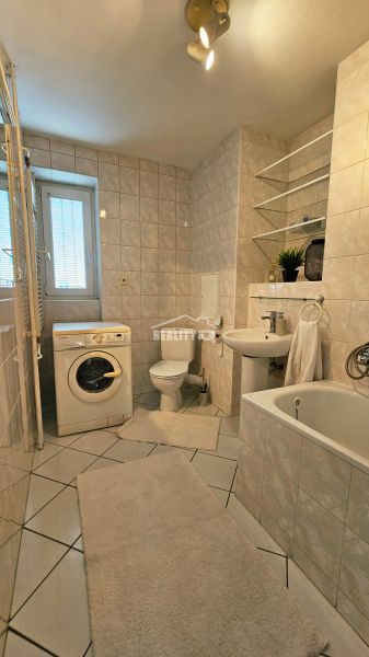 Badezimmer einer 2-Zimmer-Wohnung mit Badewanne, Waschbecken, Waschmaschine und Toilette.