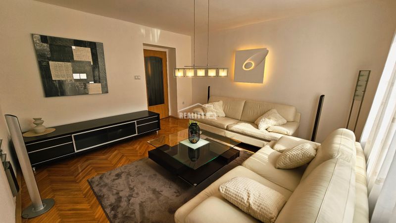 Wohnzimmer mit Ledersofa, Glastisch und Holzboden in einer Zweizimmerwohnung.