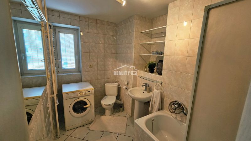 Badezimmer mit Badewanne, Dusche, Waschmaschine und Sanitäranlagen in einer 2-Zimmer-Wohnung.