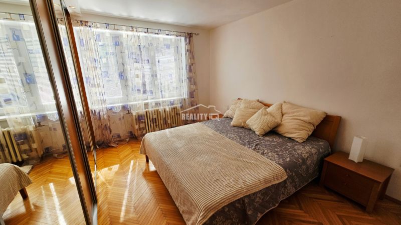 Schlafzimmer in einer 2-Zimmer-Wohnung mit Holzboden und großem Spiegel.