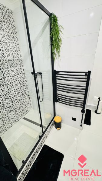 Badezimmer mit Duschkabine und schwarz-weißen Dekorationen in einer Einzimmerwohnung.