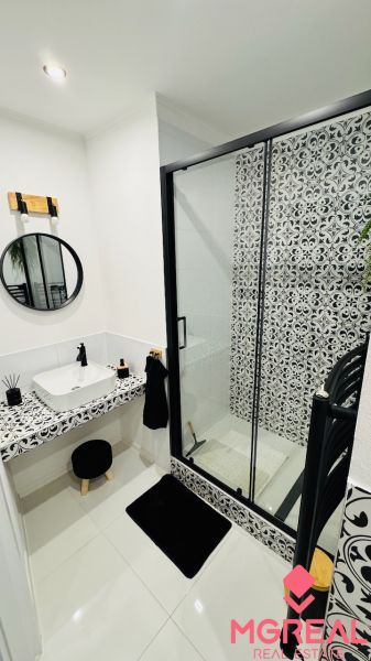 Badezimmer in einer Einzimmerwohnung mit schwarz-weißen Fliesen und einer Duschkabine.