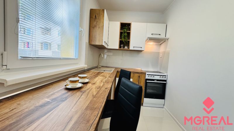 Küche in einer Einzimmerwohnung mit Holzboden, weißen Schränken und Geräten.