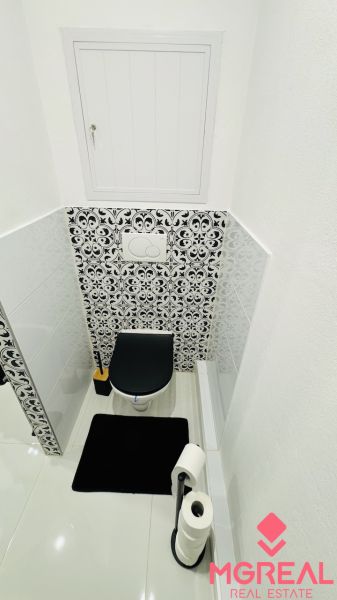 Toilette mit schwarz-weißem Fliesenmuster in einer Einzimmerwohnung.