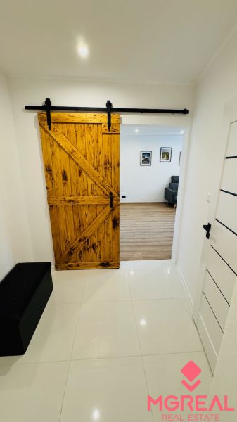 Innenraum mit Schiebetüren aus Holz, die in ein Einzimmerapartment mit Holzboden führen.