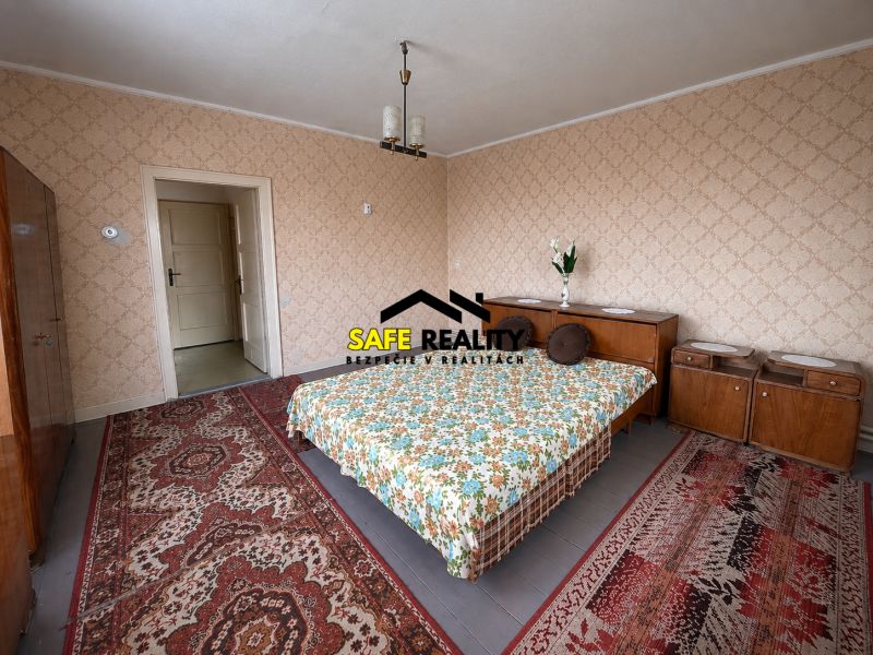 Schlafzimmer mit gemusterten Teppichen und einem Bett in einem Einfamilienhaus mit Holzelementen.