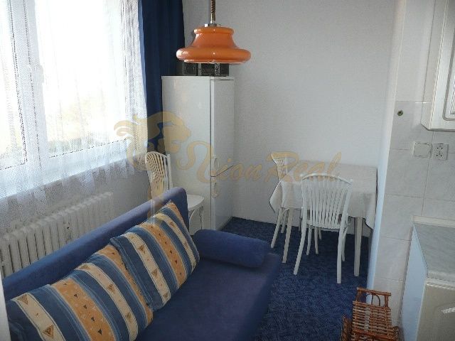 Ein Zimmer mit einem blauen Sofa und einer orangefarbenen Lampe in einer Zweizimmerwohnung.