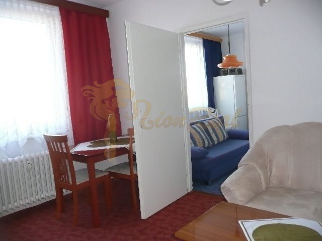 Wohnzimmer in einer Zweizimmerwohnung mit gepolstertem Sofa und Esstisch.