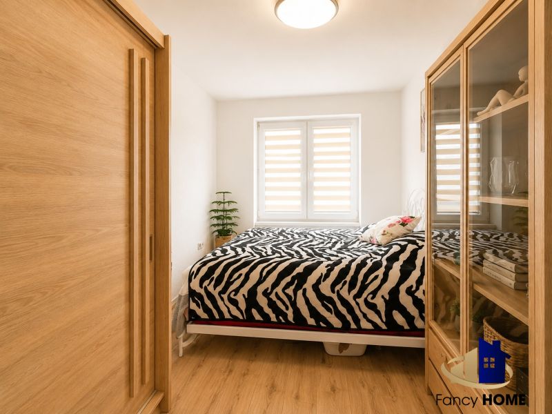 Schlafzimmer in einer 2-Zimmer-Wohnung mit Holzboden und Zebradecke.