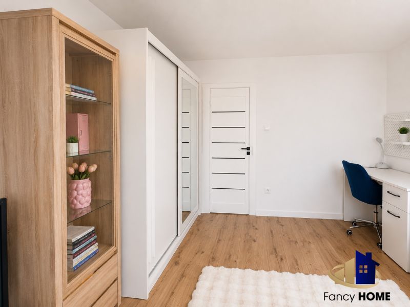 Arbeitsbereich mit weißem Tisch, blauem Stuhl und Holzboden in einer Zweizimmerwohnung.