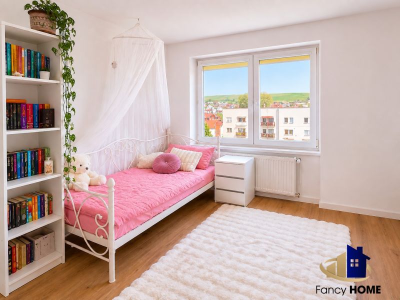 Ein Zimmer in einer 2-Zimmer-Wohnung mit einem weißen Bett, einem Regal und einem Boden in Holzoptik.