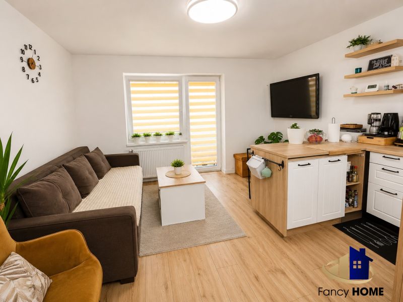Wohnzimmer in einer Zweizimmerwohnung mit Sofa und Küchenzeile, Boden mit Holzdekor.