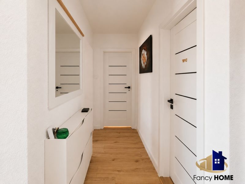 Ein heller Flur in einer 2-Zimmer-Wohnung mit weißen Türen und einem Boden in Holzoptik.
