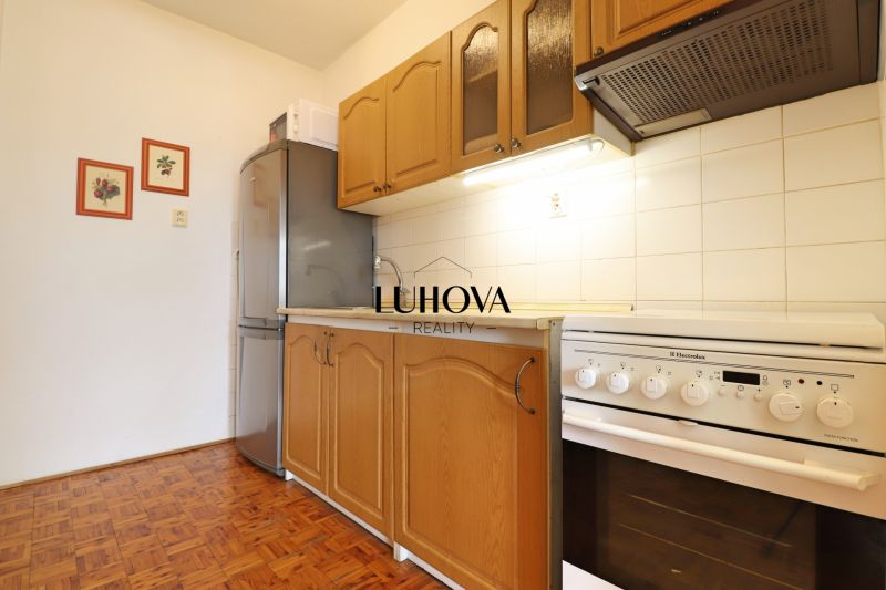 Küche in einer 2-Zimmer-Wohnung mit Holzboden und weißen Fliesen.
