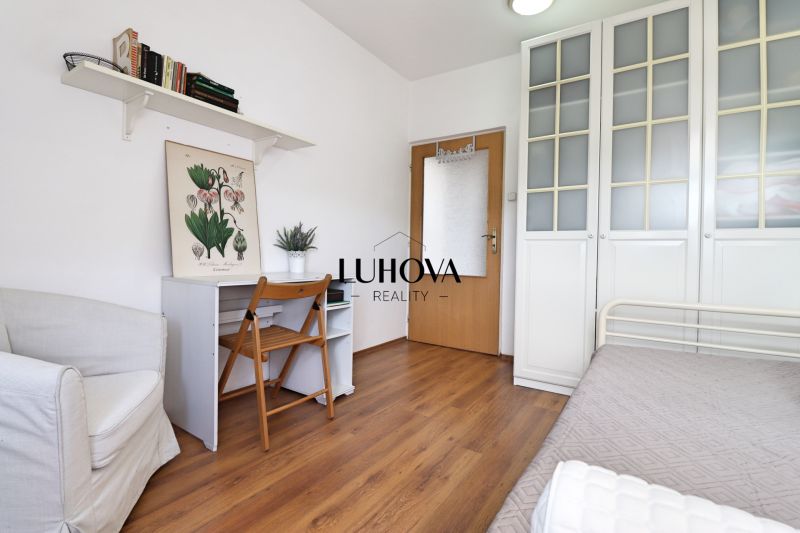 Ein Zimmer in einer 2-Zimmer-Wohnung mit einem Boden in Holzoptik, ein Schreibtisch und ein Stuhl.