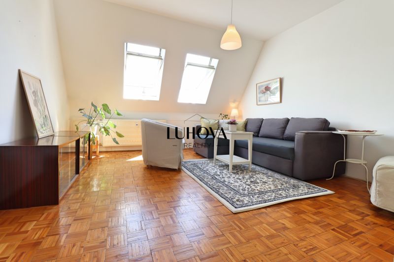 Wohnzimmer in einer 2-Zimmer-Wohnung mit Fenstern und Boden in Holzoptik.