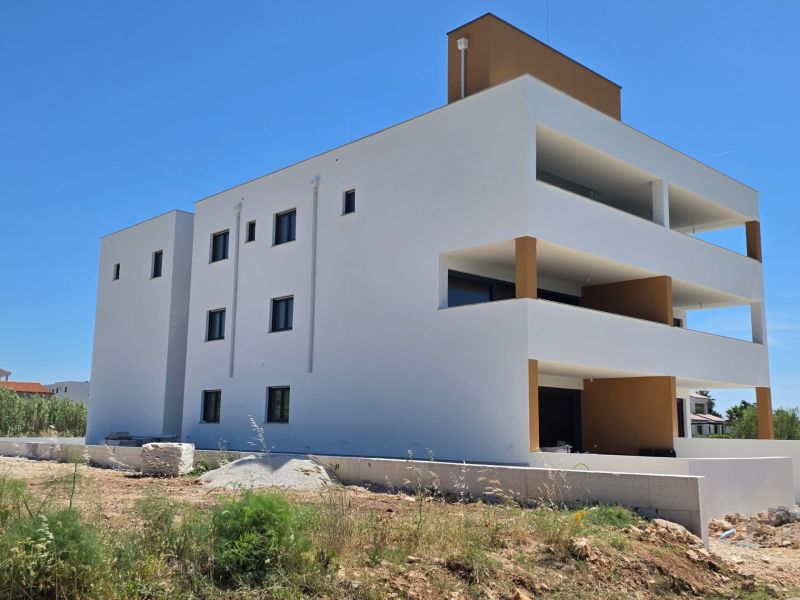 Weißes Wohnhaus mit Balkonen in Privlaka gegenüber dem blauen Himmel, 3-Zimmer-Wohnung.