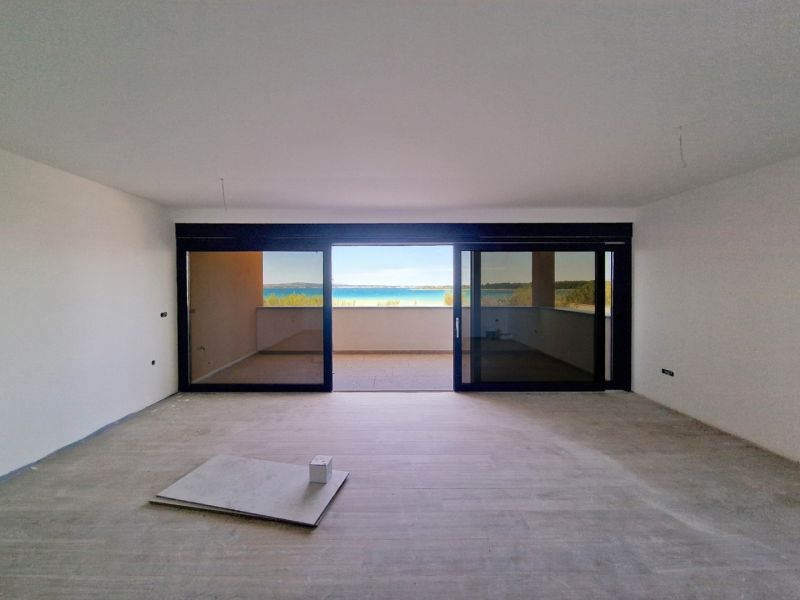 Wohnzimmer einer Dreizimmerwohnung mit Glaswand und Boden in Holzoptik.