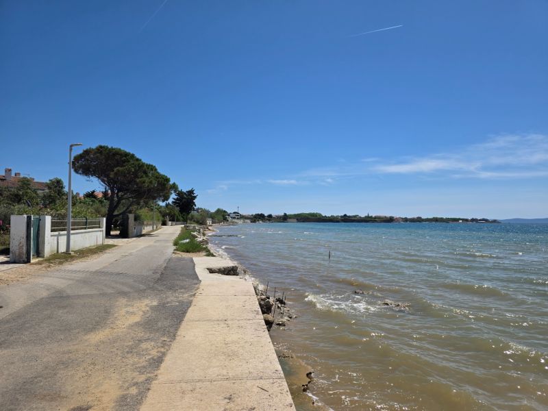 Die Küstenstraße in Privlaka verläuft bei sonnigem Wetter am Meer entlang.