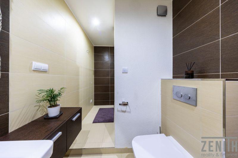 Badezimmer in einer 3-Zimmer-Wohnung mit braunen und beigen Fliesen und grüner Dekoration.