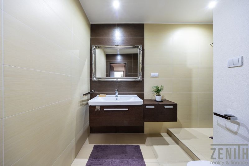 Badezimmer in einer 3-Zimmer-Wohnung mit weißem Waschbecken, dunklem Holzdekor und Spiegel.