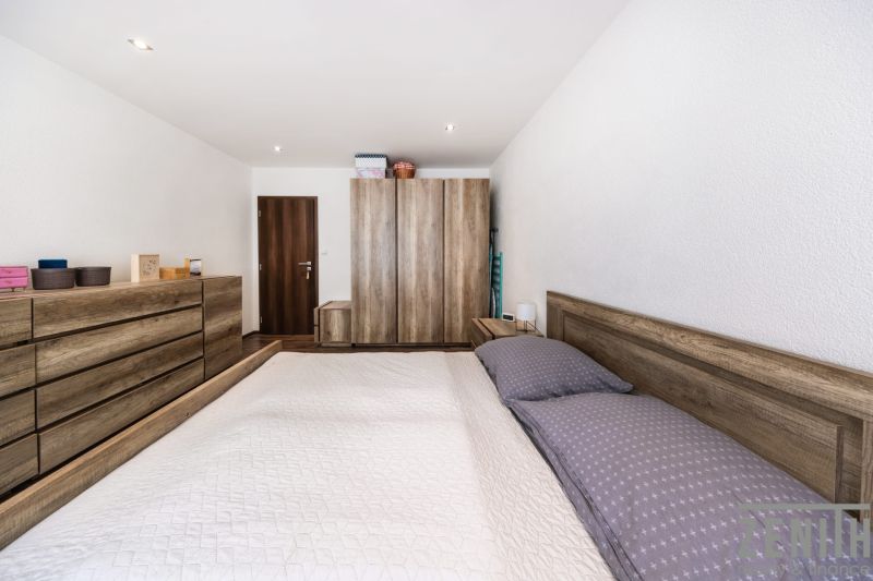 Schlafzimmer in einer 3-Zimmer-Wohnung mit Holzmöbeln und einem Boden in Holzoptik.