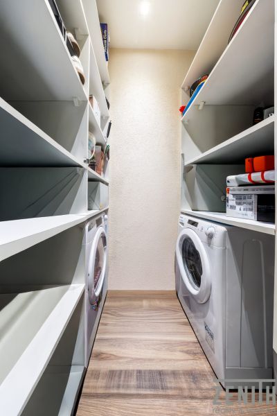 Stauraum mit Regalen und Waschmaschine in einer 3-Zimmer-Wohnung mit Holzboden.