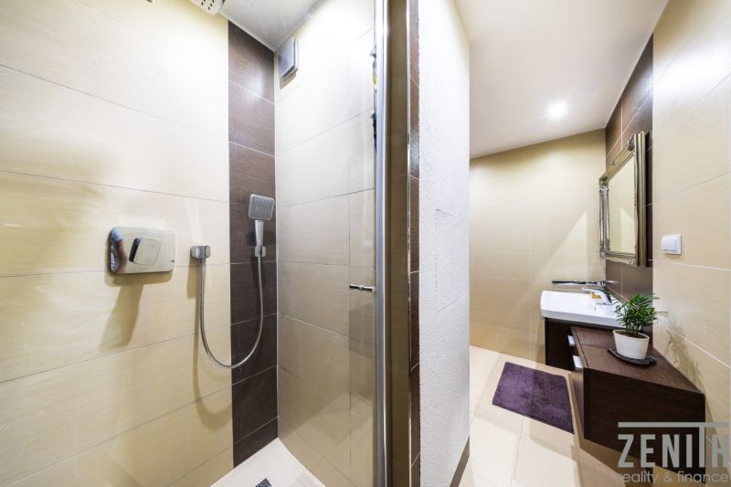 Badezimmer mit Dusche, helle Fliesen und Waschbecken, 3-Zimmer-Wohnung.