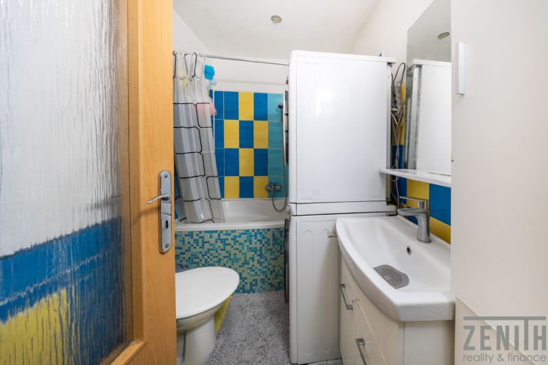 Badezimmer in einer 3-Zimmer-Wohnung mit farbigen Fliesen und einer Waschmaschine.