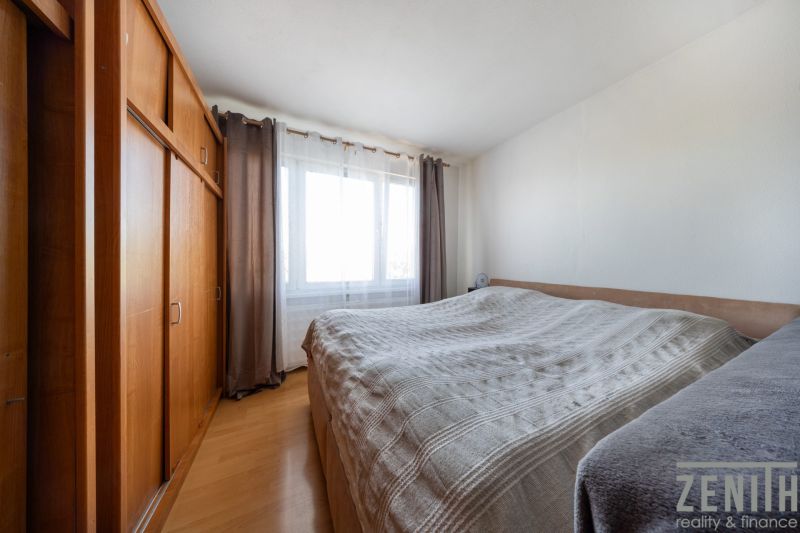 Schlafzimmer mit Bett, großem Schrank und Boden mit Holzdekor in einer 3-Zimmer-Wohnung.