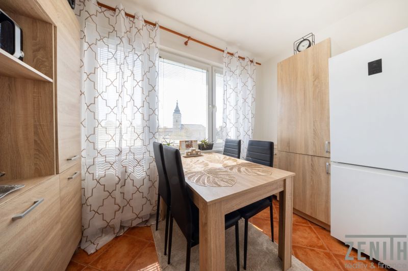 Ein Esstisch mit vier Stühlen in einer 3-Zimmer-Wohnung, Vorhänge mit geometrischem Muster.