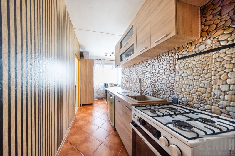 Küche in einer 3-Zimmer-Wohnung mit Küchenzeile und Fliesen in Steinoptik.