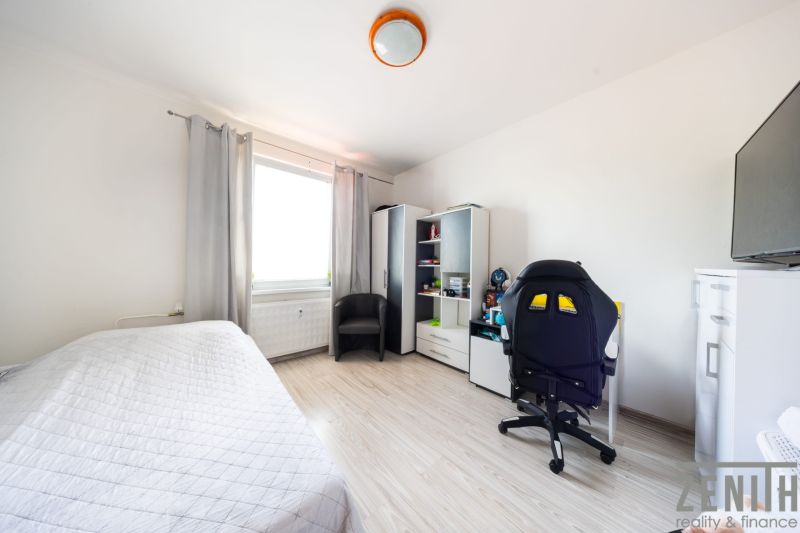 Helles Zimmer in einer 3-Zimmer-Wohnung mit Holzboden und Schreibtisch.