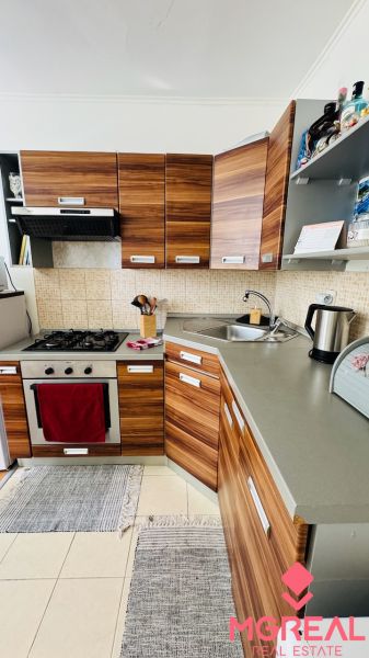 Küche in einer Einzimmerwohnung mit Schränken in Holzoptik und Geräten.