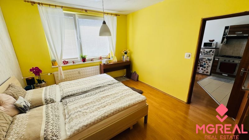 Schlafzimmer in einer Einzimmerwohnung mit Holzboden und gelben Wänden.